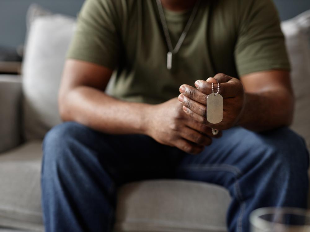 Closeup of veteran holding dog tags necklace in hands during therapy session