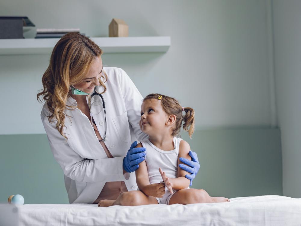 Child sits on a hospital room bed and looks at a doctor.