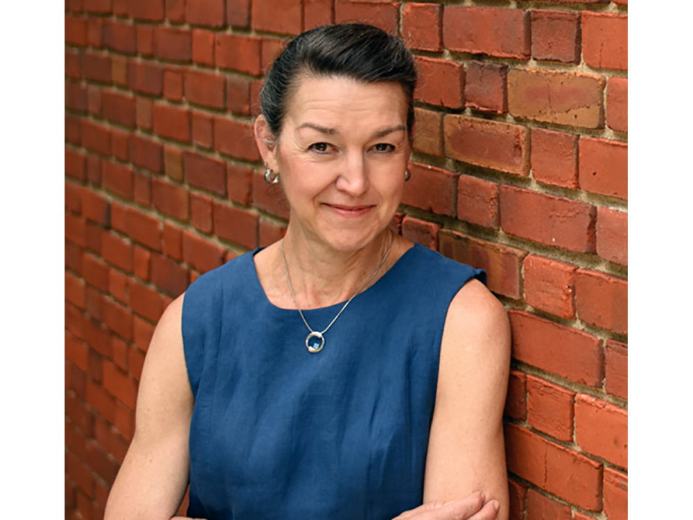 Author and historian Laura Edwards standing leaning against a brick wall