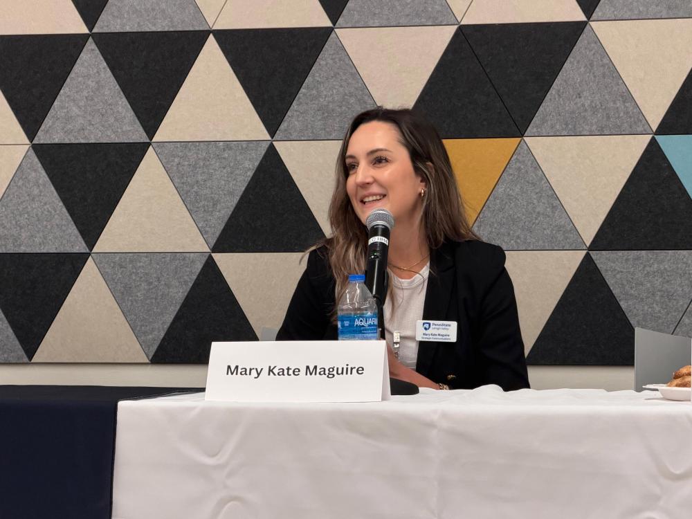 Mary Kate Maguire sitting at a table with a microphone facing an audience at Penn State