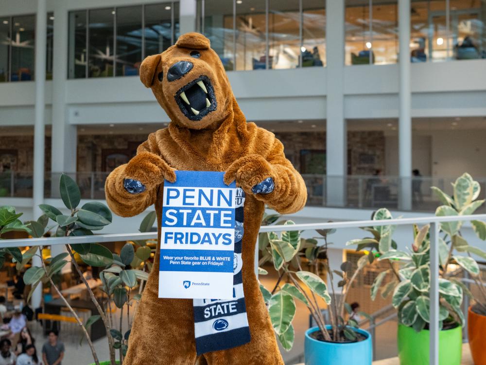 The Nittany Lion mascot holds a sign promoting "Penn State Fridays"