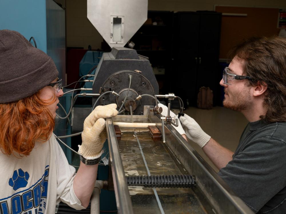 two students working on a piece of machinery