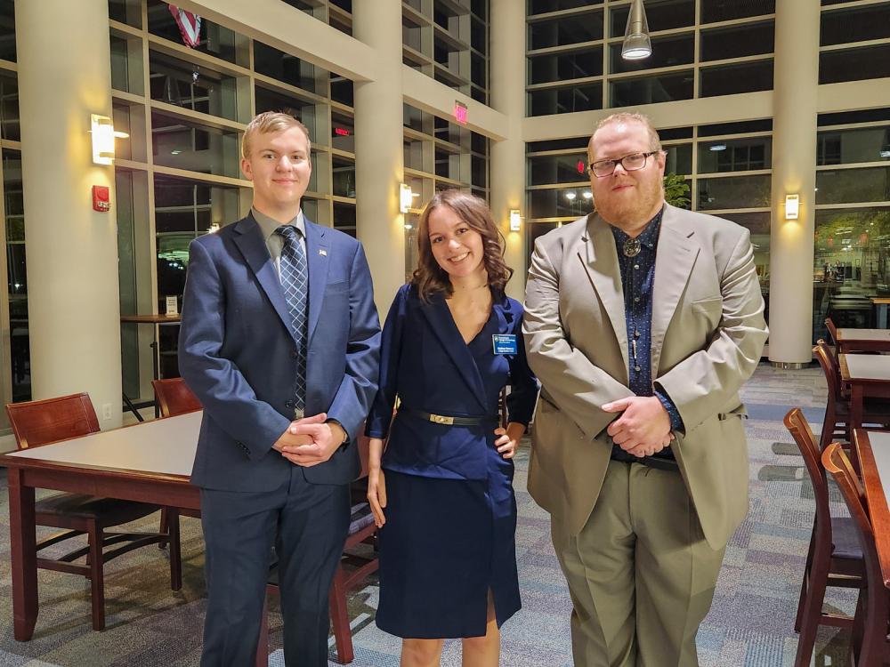 Three people pose for a photo in a lobby
