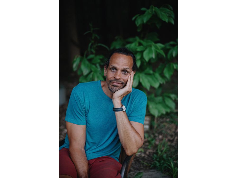 Portrait of poet Ross Gay sitting in front of tree
