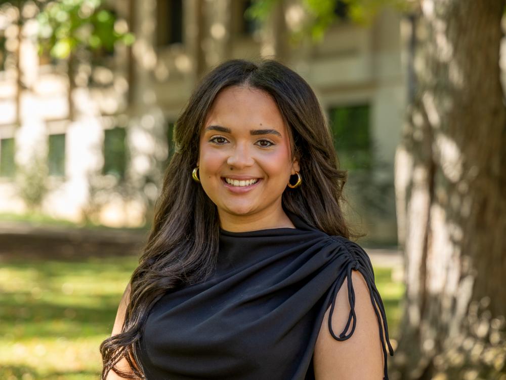 Alexa Sanchez stands outside in front of a tree and building on the University Park campus.