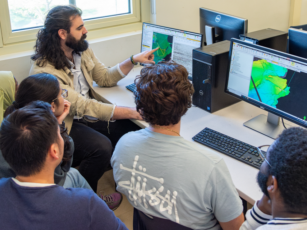Six students gather around a computer in a computer lab looking at 3D seismic and well data.