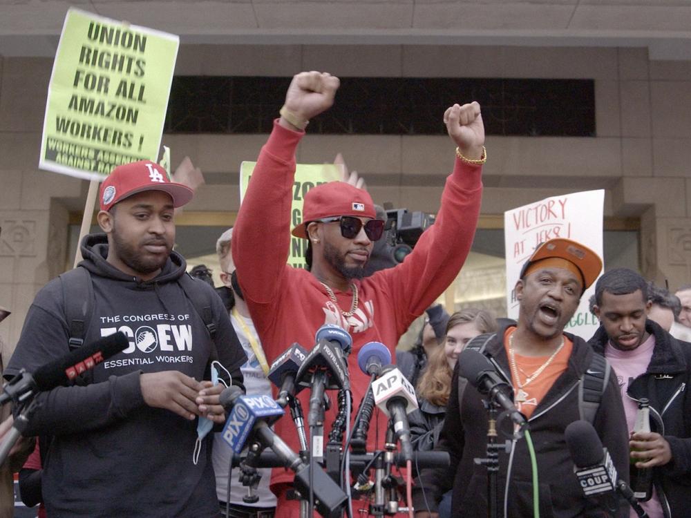 Several men stand at microphones during a demonstration to organize a union