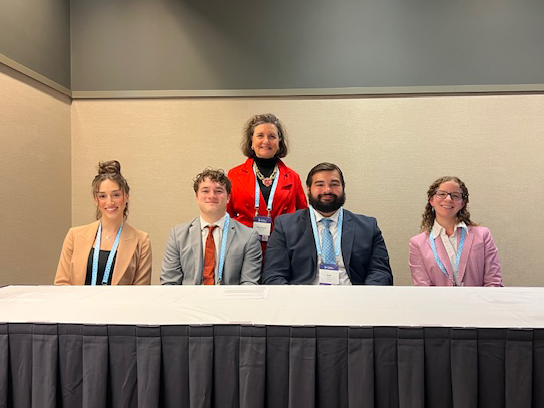 From left to right, Emma Gatto, Bjorn Sigurdsson, Alexander Mann and Rachel White sit at a table, with Rosemary Martinelli standing behind them during the Global Impact Forum in Pittsburgh.