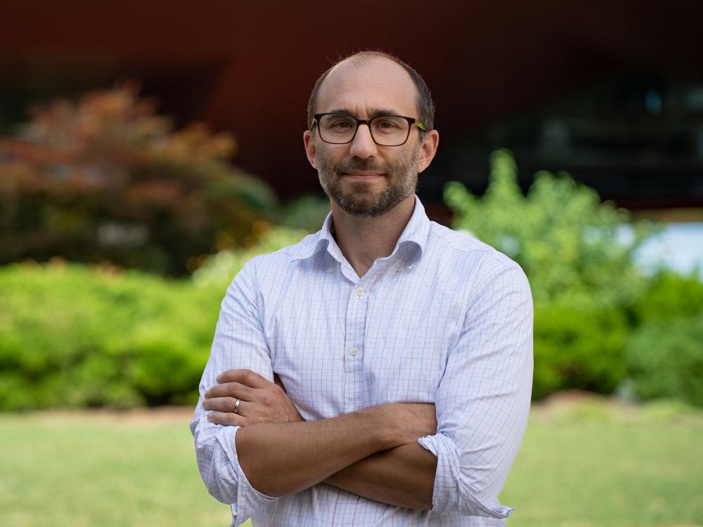 Patrick Drew standing outside, with arms crossed, looking at the camera