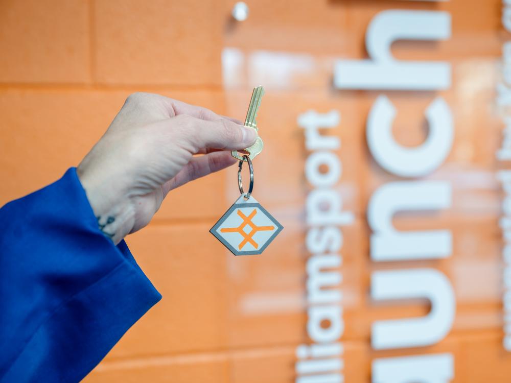 A hand holding up a key with a launchbox logo fob