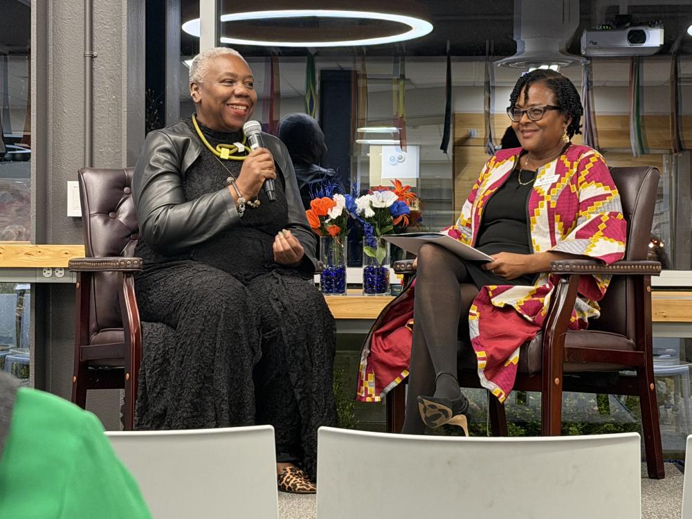Two women sitting and speaking using a microphone
