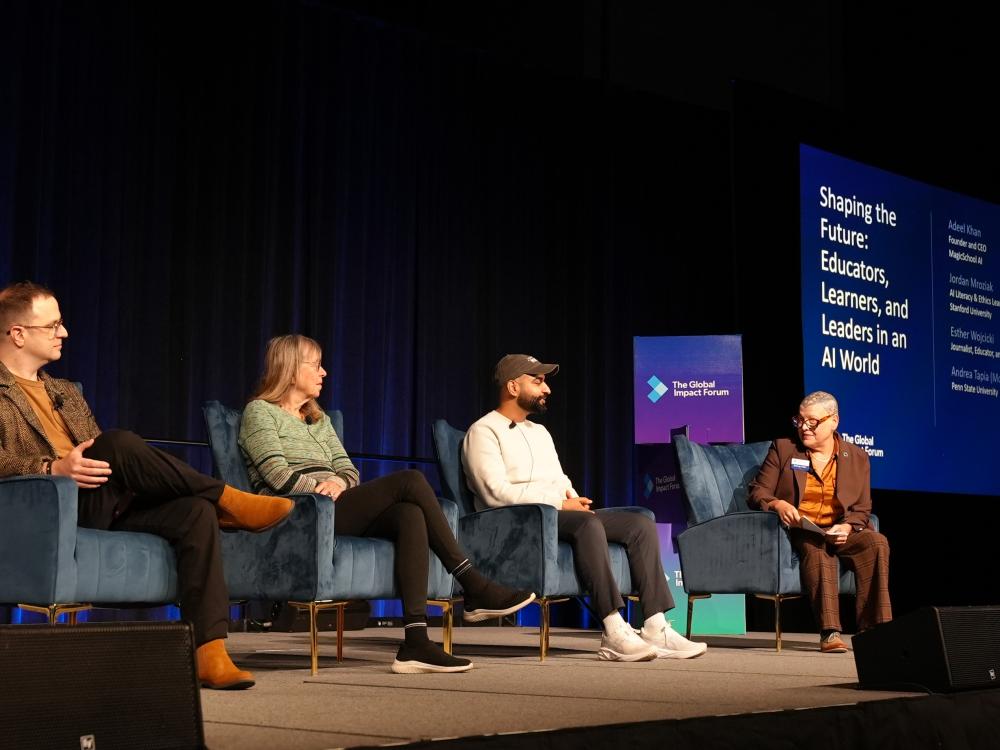 A panel discussion at The Global Impact Forum with four speakers seated on stage in blue chairs.