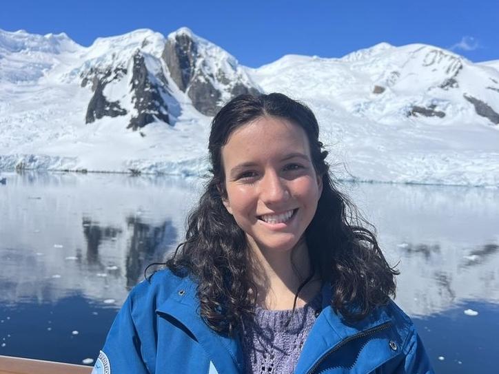 Photo of Emma Chaplin on boat in Antarctica with snowy mountains in background