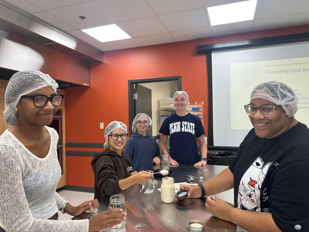 Five students in hairnets stand around a table and look at the camera