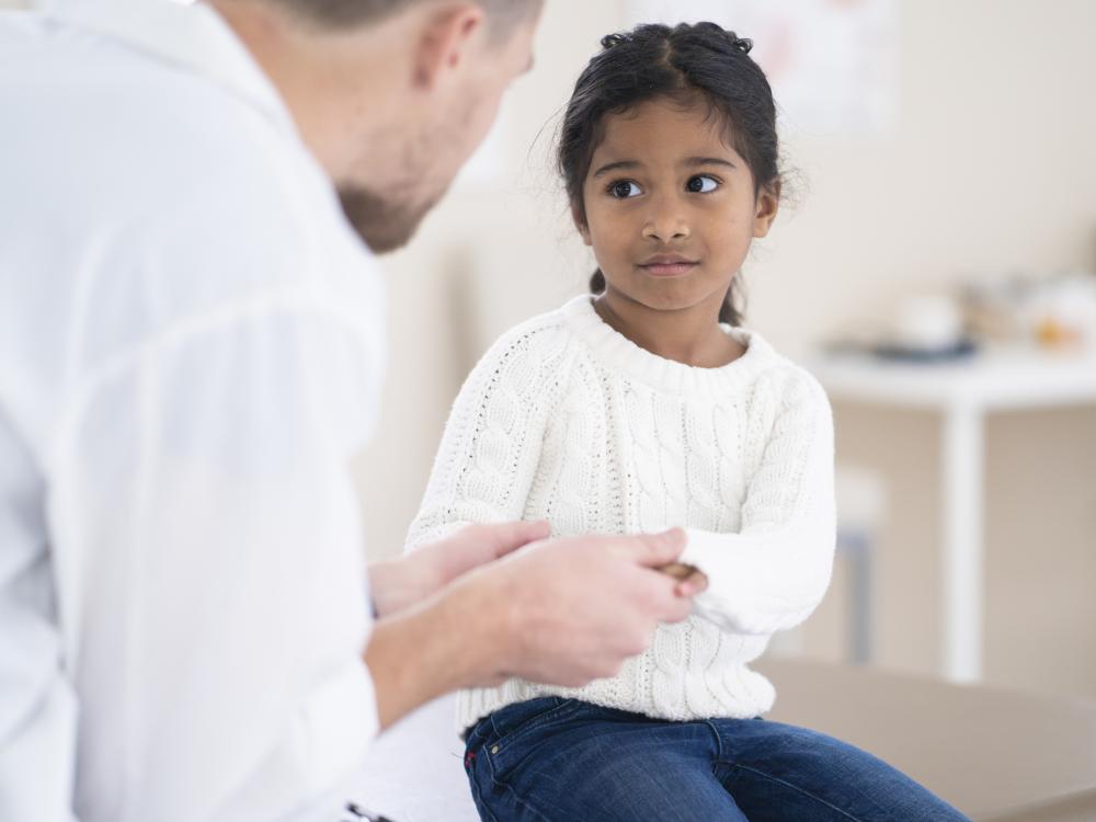 Small child being examined by a physician in a white coat