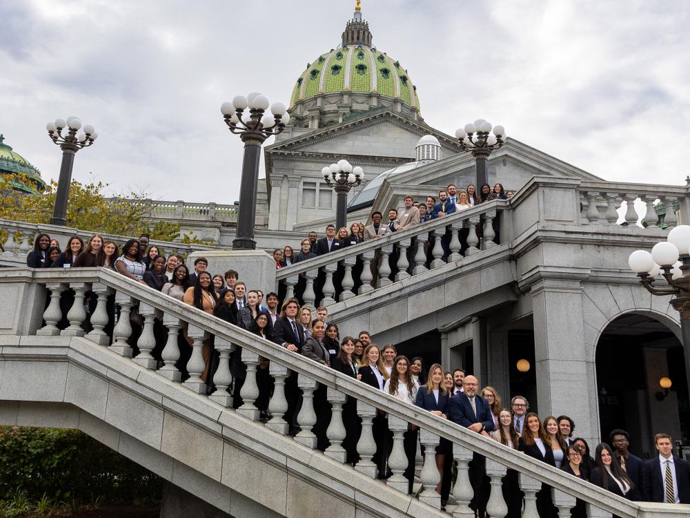The full group of students stands on a double staircase leading to the Pennsylvania Capitol Building