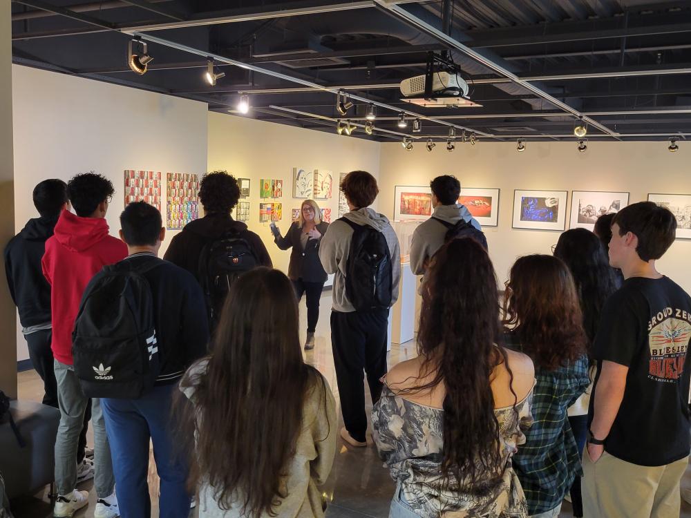 students gathered listening to a speaker in an art gallery