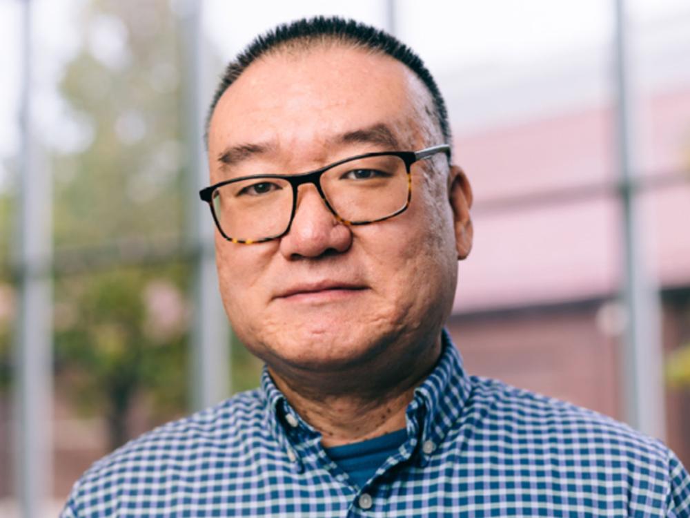 headshot of person with very short dark hair and wire-rimmed glasses