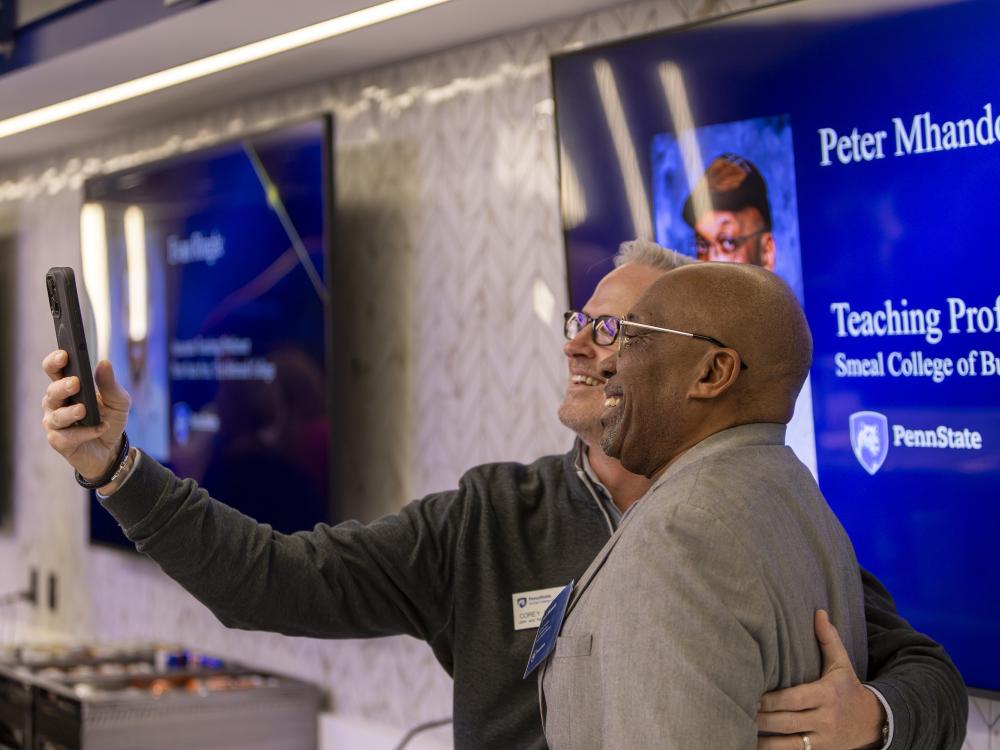 Two people taking selfie in front of a television screen
