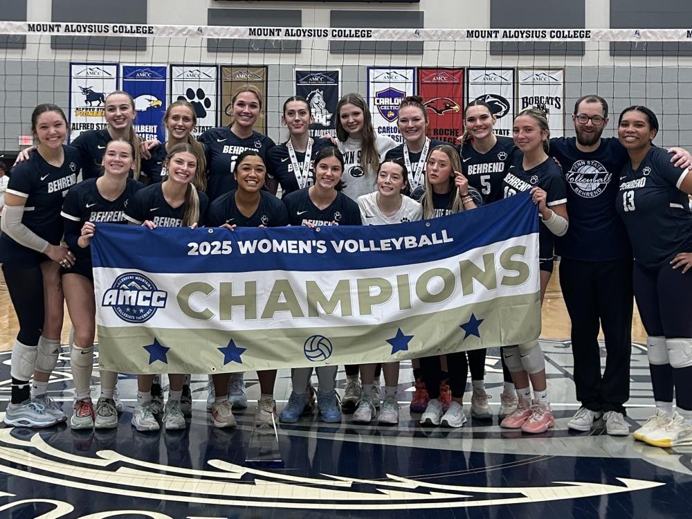 The Penn State Behrend women's volleyball team poses with the AMCC championship banner.