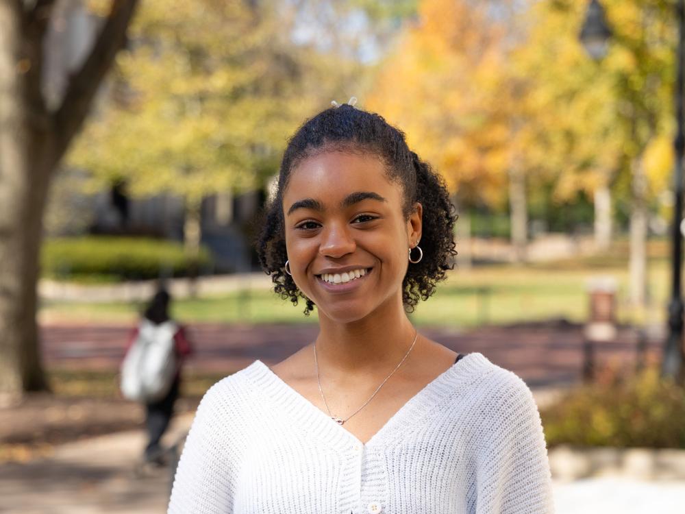 Simone Warren stands outside with fall trees in the background at Pattee Mall.