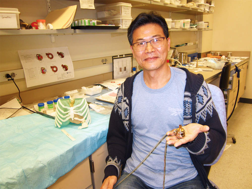 Scientist sitting in a lab and holding a prototype of a heart pump