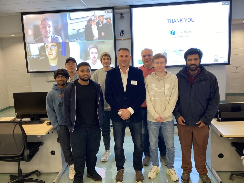 students standing in classroom with Jason Reed in front of two projectors with students