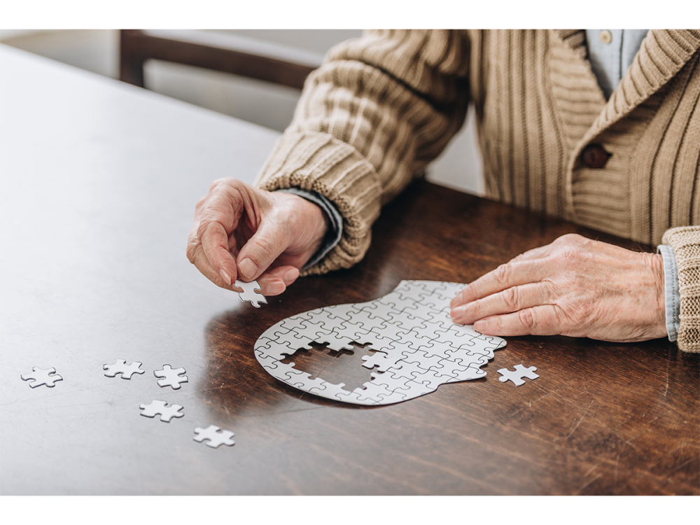 Cropped view of older man working on a puzzle