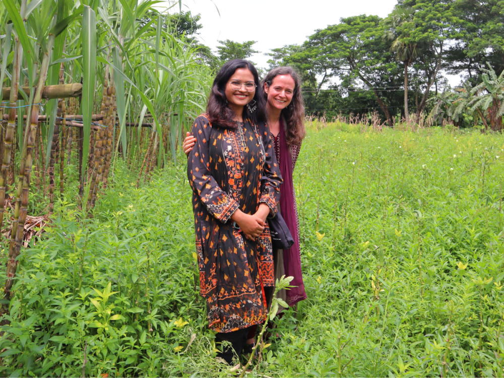 Jessica Grembi and Nazifa Tabassum in a grassy field smiling for the camera