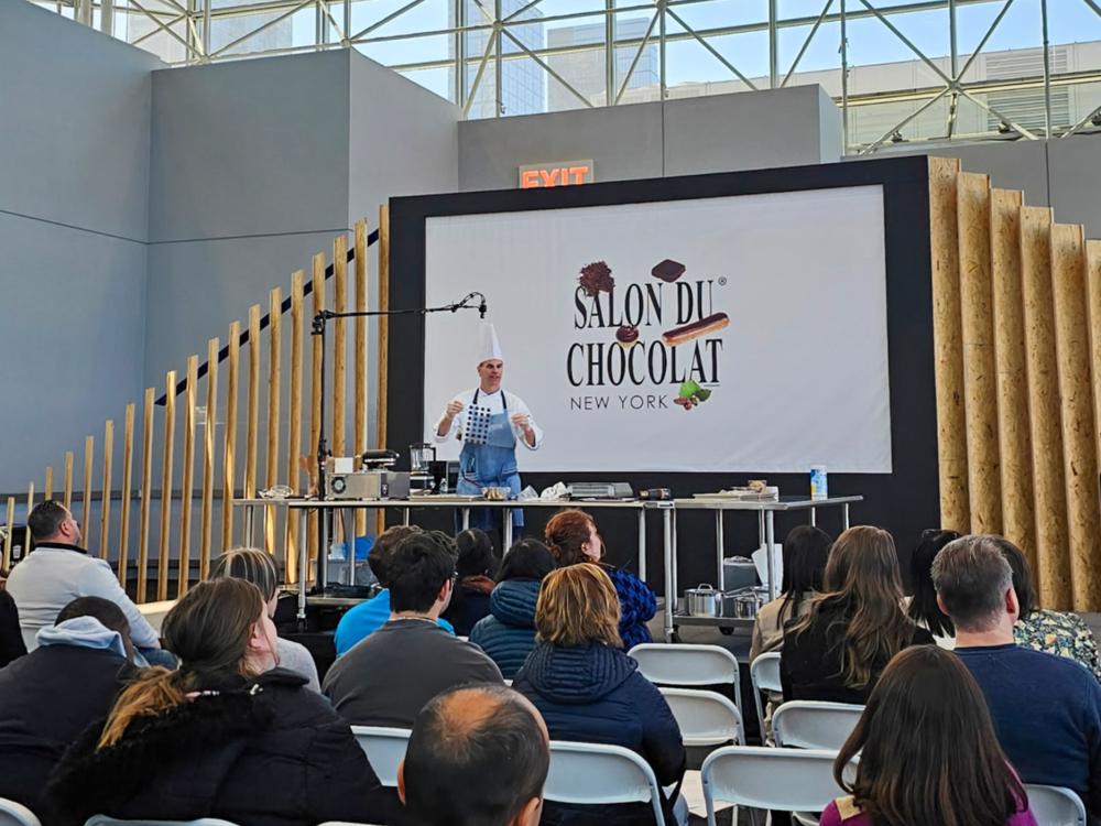 A man dressed in chef's uniform teaches a workshop in front of participants