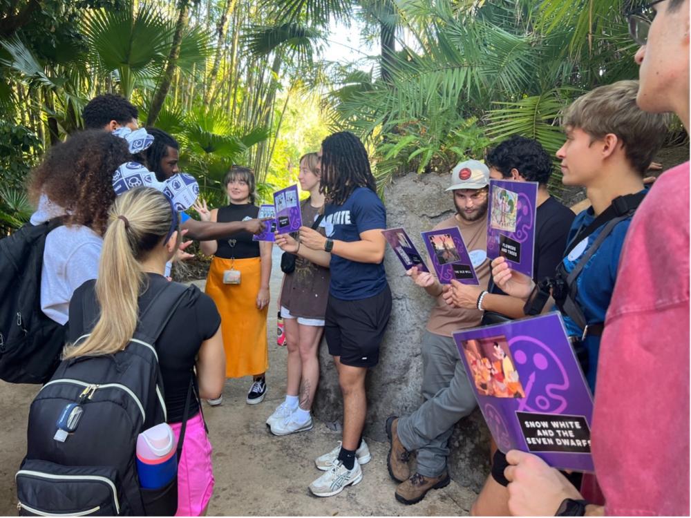 A group of Penn State New Kensington students stand together in a wooded area at Disney’s Animal Kingdom, holding printed cards and discussing design concepts as part of an engineering-focused workshop.