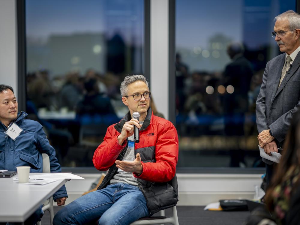 A person in a red jacket holding a microphone.
