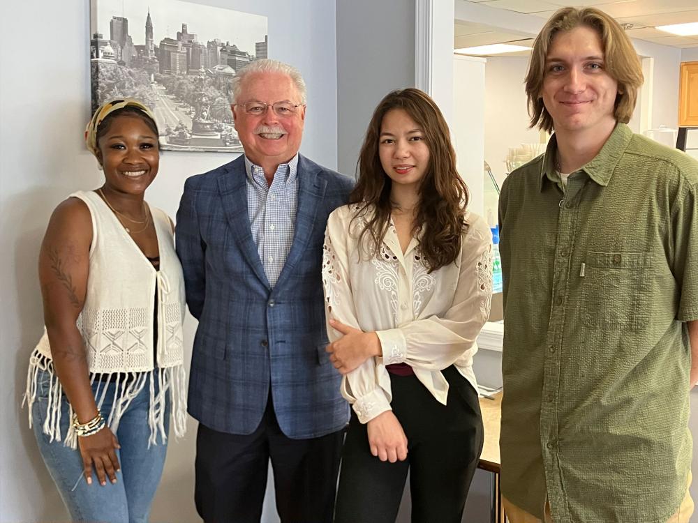 Four people standing inside and looking at camera