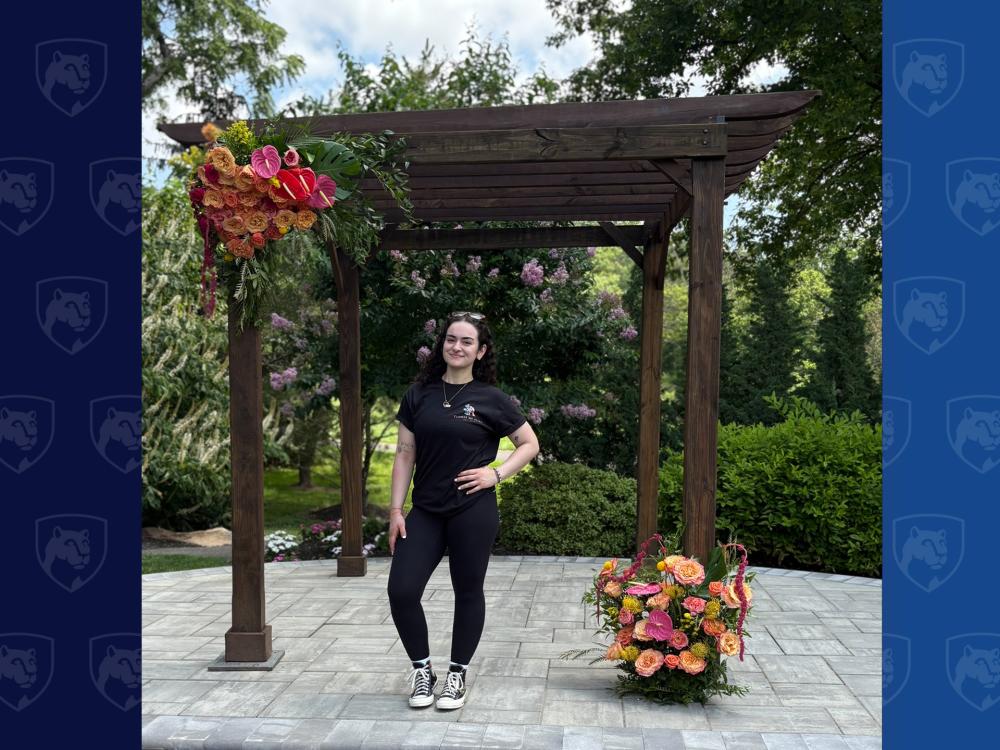 woman standing under wooden arbor with flowers