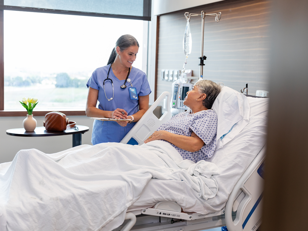 Doctor speaking with person lying in hospital bed