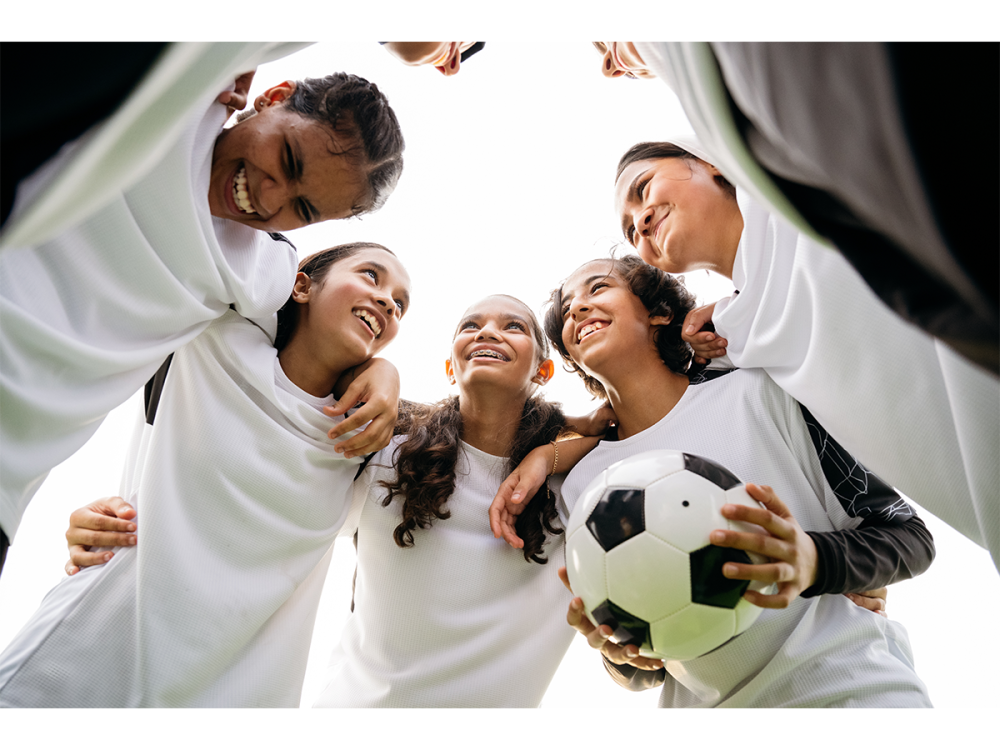 Female athletes in a huddle with soccer ball