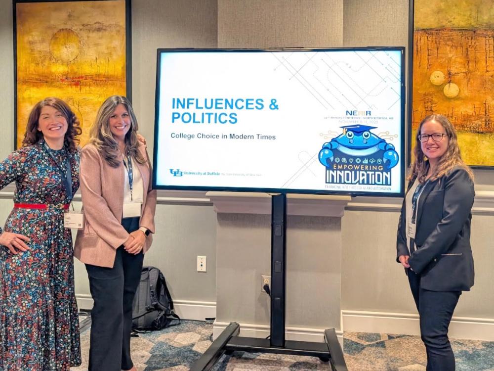 three women standing in front of a projection screen 
