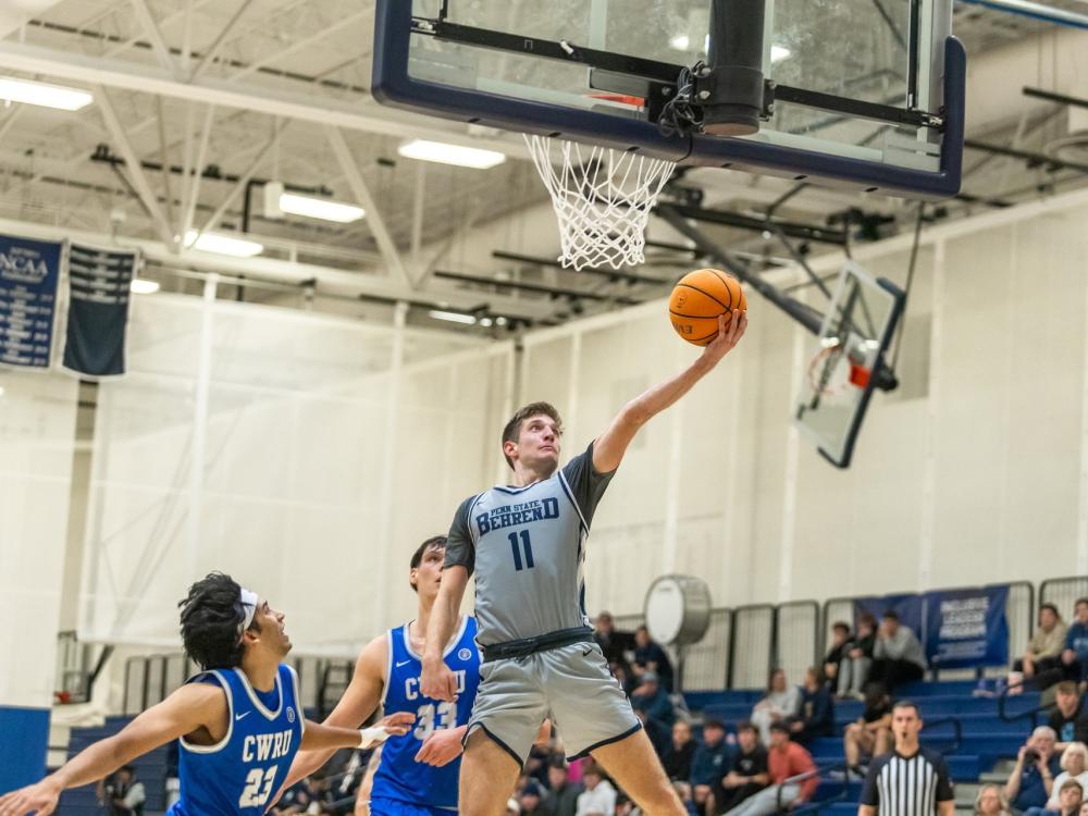A member of the Penn State Behrend men's basketball team makes a layup.
