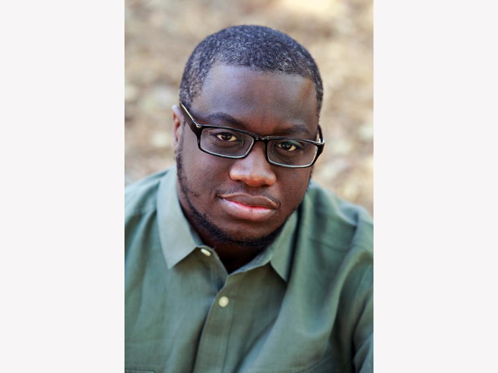 Award-winning fiction writer Rion Amilcar Scott wearing a green shirt