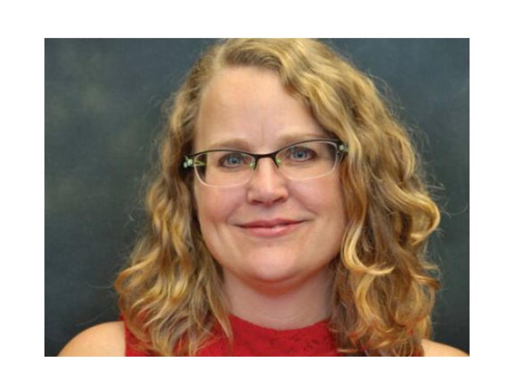 Woman with curly blonde hair and glasses.