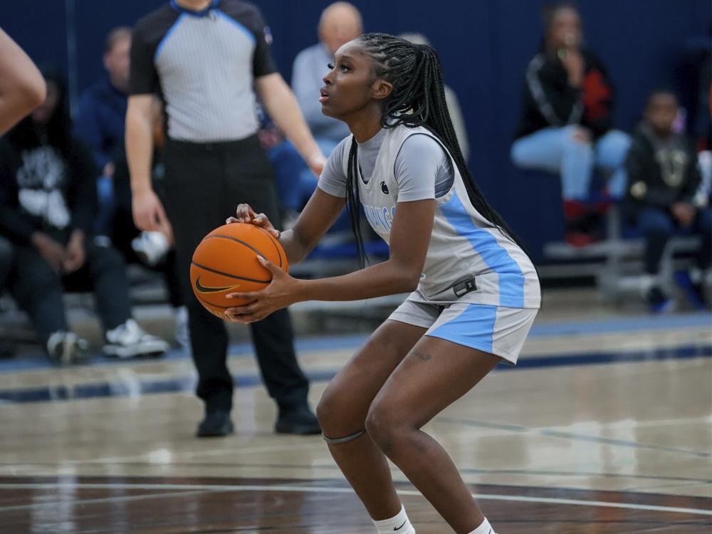 Women's Basketball player holds a basketball and looks towards the hoop off camera preparing to shoot a free throw.