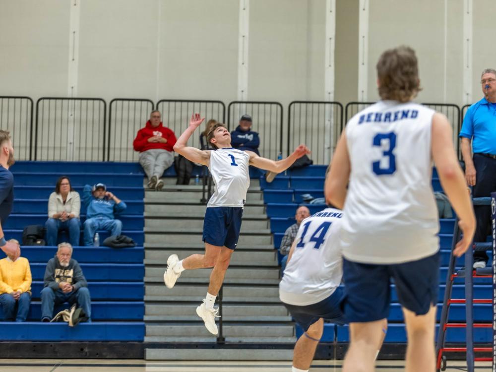 A member of the Penn State Behrend men's volleyball team jumps to spike the ball.