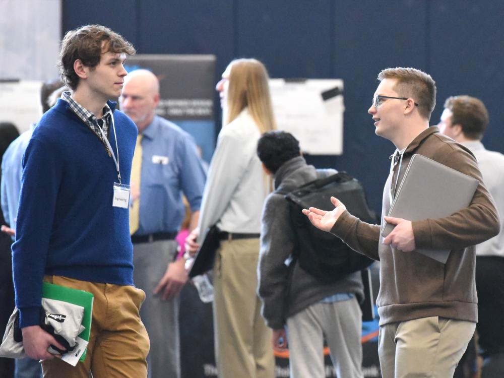 Two male students talk during Penn State Behrend's spring career fair.