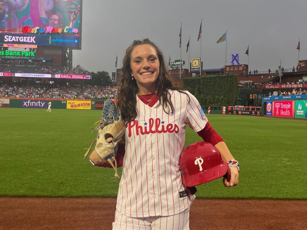 woman in Phillies uniform on baseball field