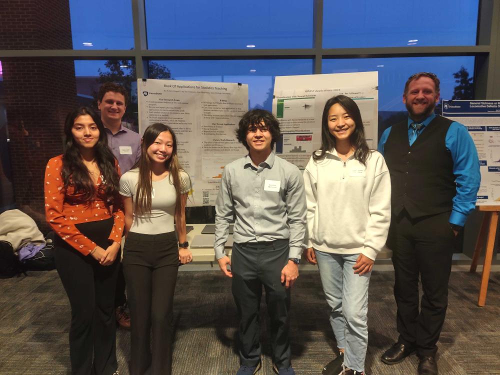 students and professor Neil Hatfield stand in front of a poster about BOAST