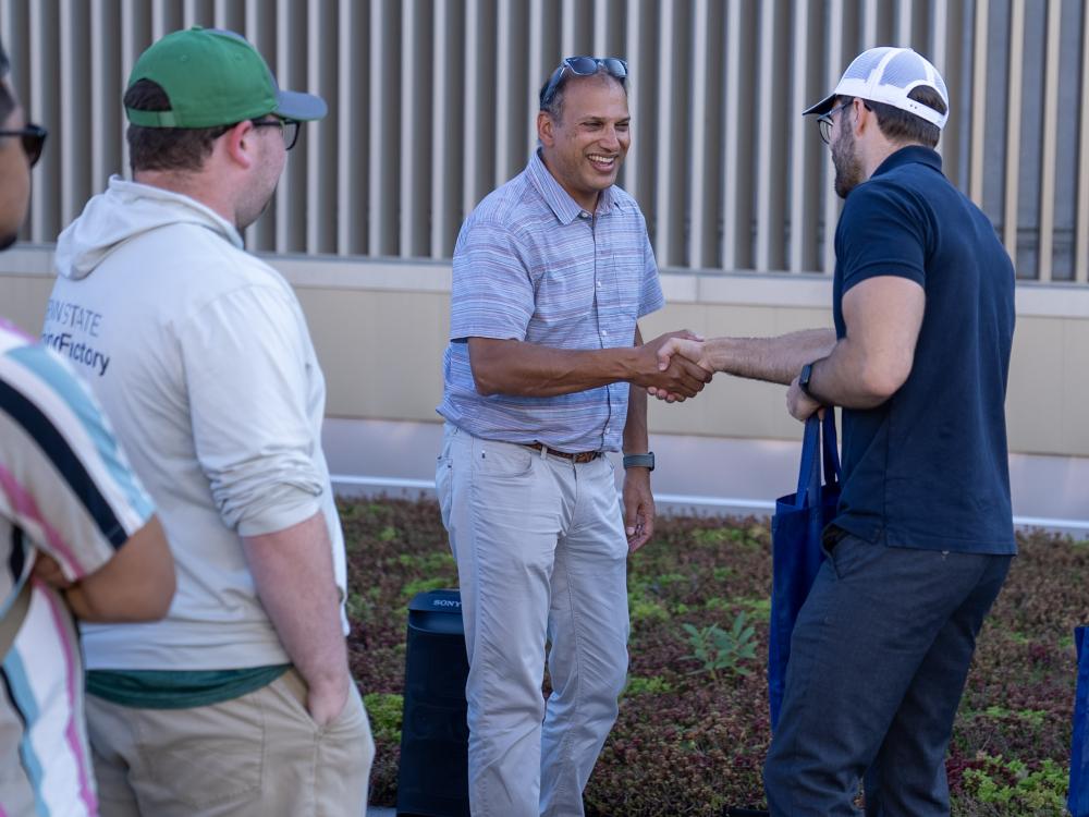 Two men shaking hands while another looks on