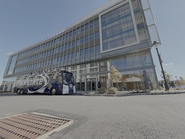 Penn State van in front of a large window cover building