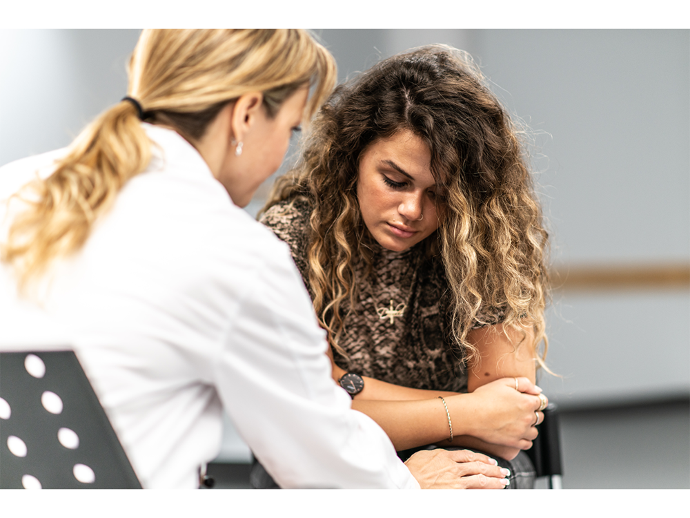 Young person seated facing a therapist in a white coat