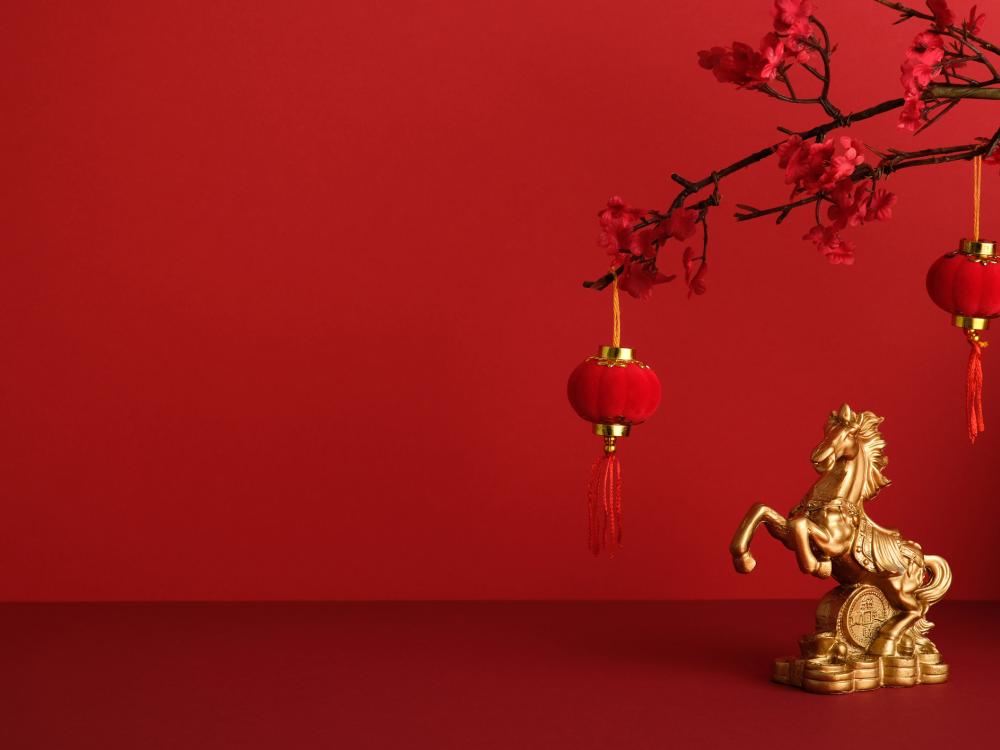 A golden horse statue with hanging lanterns and red flowers, on a red background