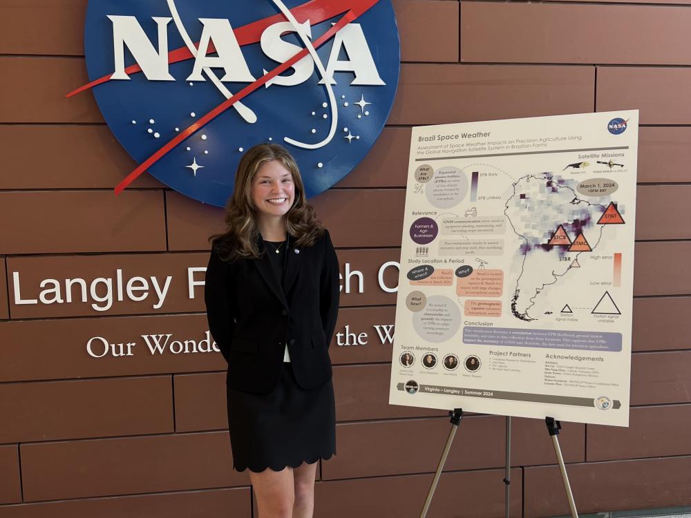 Scholar Ann Ehrlich poses in front of the NASA sign